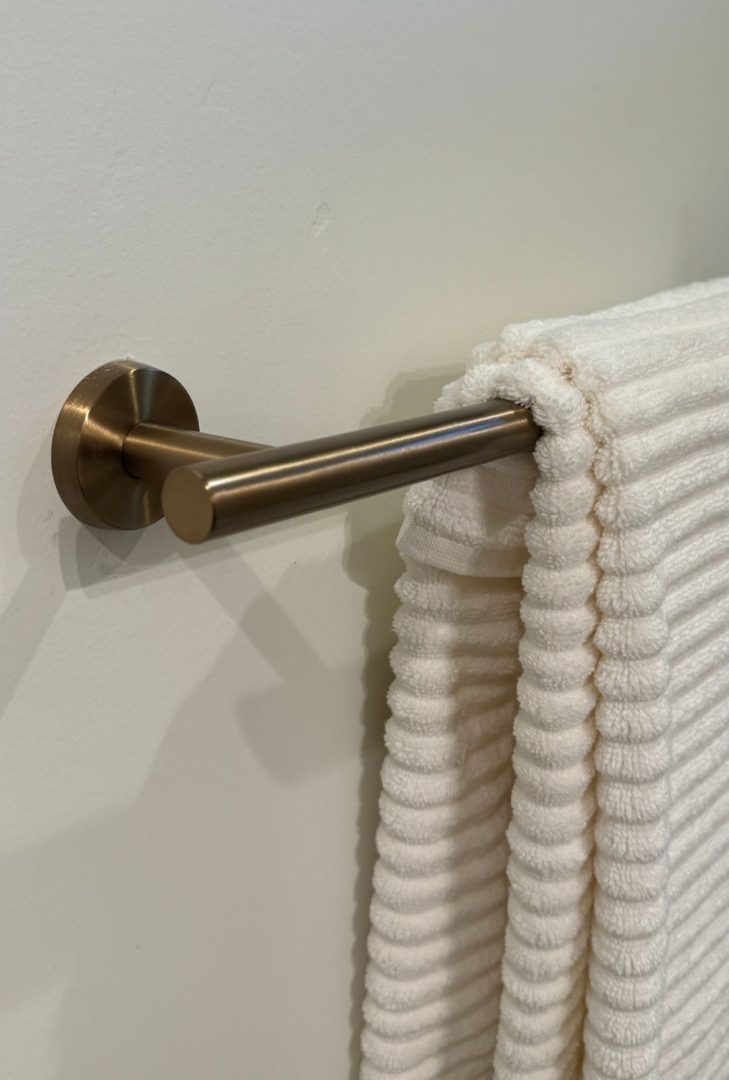 Amerock Arrondi bathroom hardware collection in a stunning golden champagne finish, featured in a Monarch Homes build. The collection includes towel bars, robe hooks, and drawer pulls, adding a warm, luxurious touch to the bathroom space while perfectly complementing modern and elegant design elements.